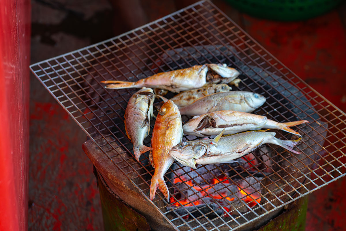 Kambodża - ryby złowione przez uczestników wycieczki łodzią pieką się na grillu.